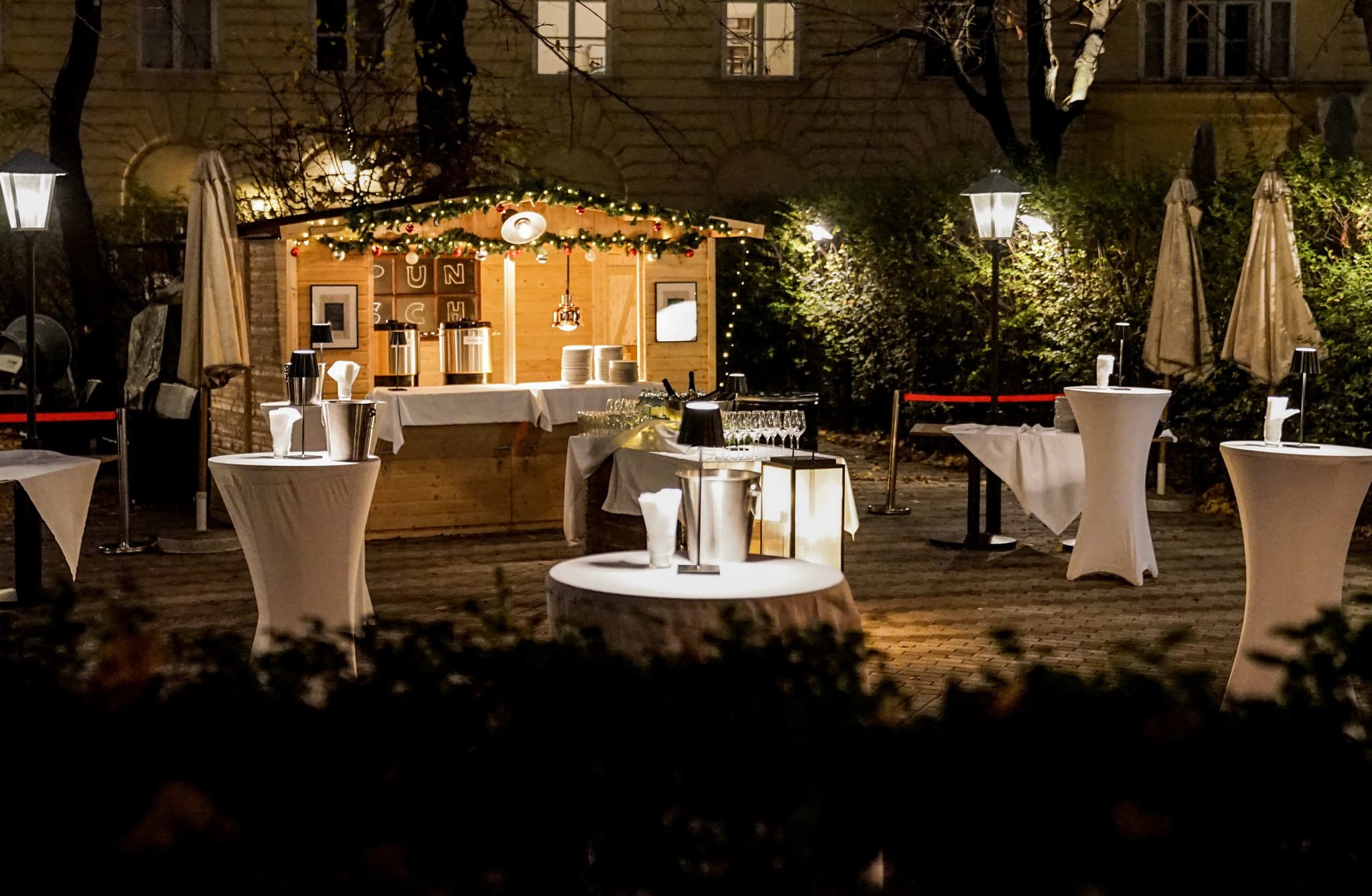 Punschstand Gastgarten Wien 1010 - Winterliche Outdoor-Weihnachtsfeier mit Stehtischen und Laternen im Innenhof Café Diglas Schottenstift